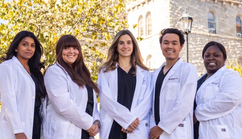 students in white coats smiling at camera